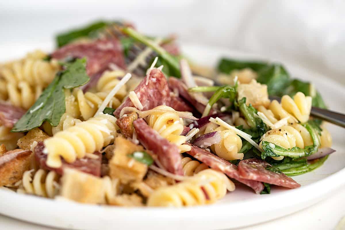 salami pasta salad on white plate with fork