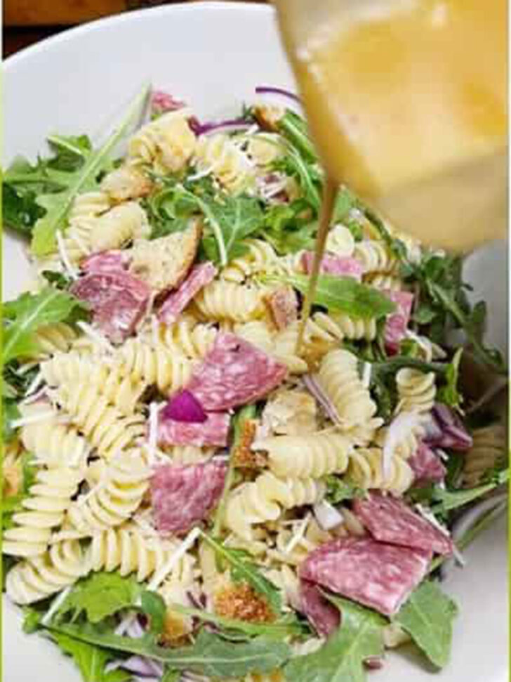 Adding the homemade pasta salad dressing to the salad.