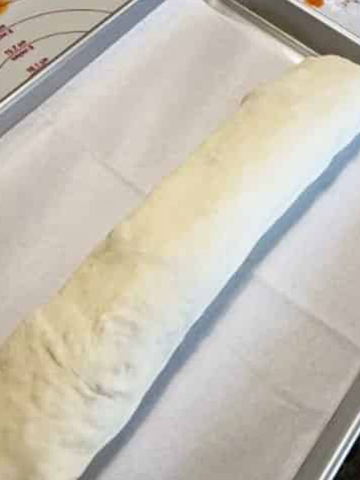 Rolled stromboli on a parchment-lined baking sheet.