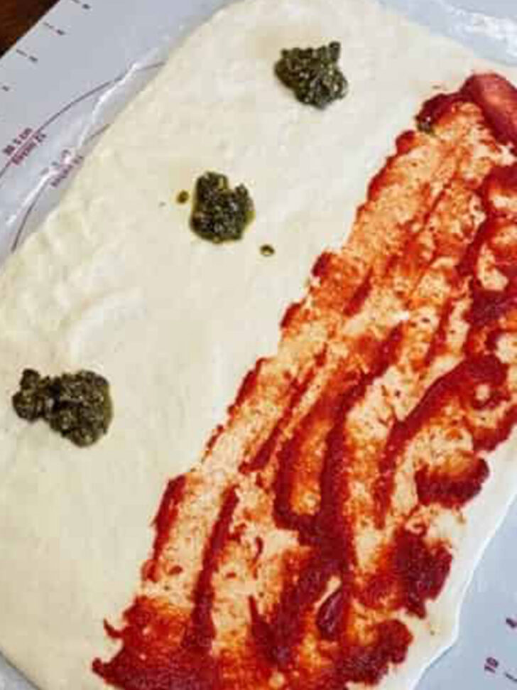 Adding the pesto to the empty side of the dough.