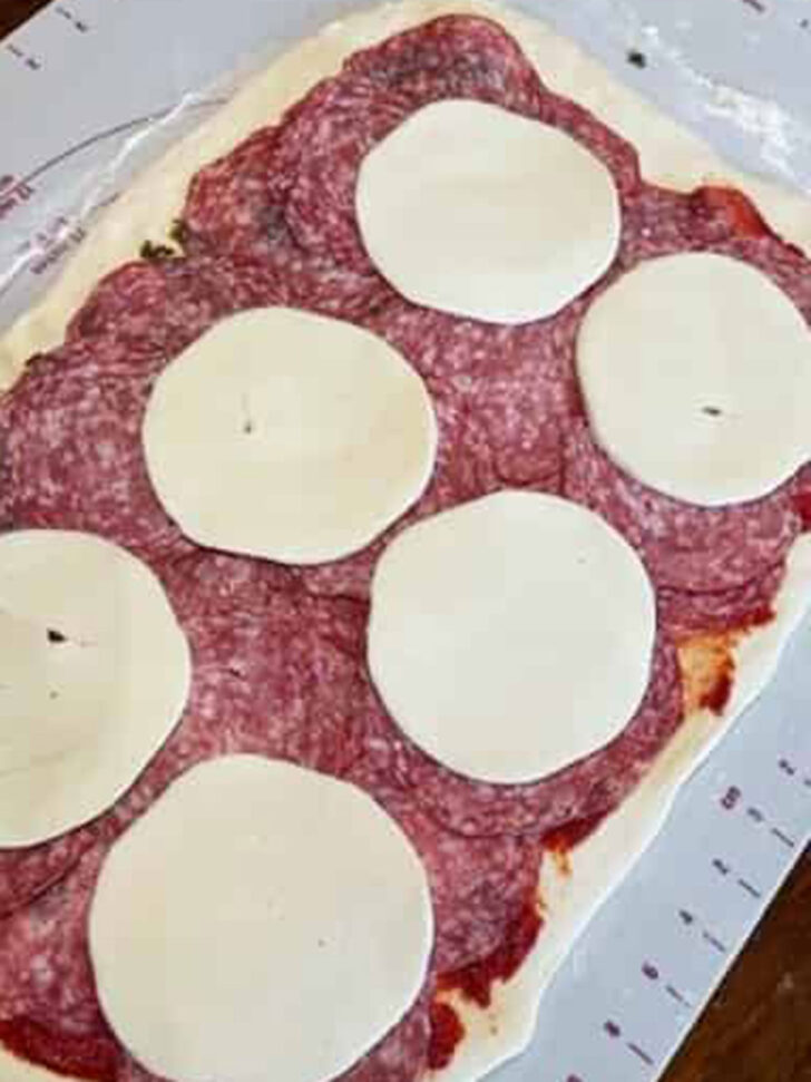 Adding the cold meat and cheese on top of the stromboli dough.