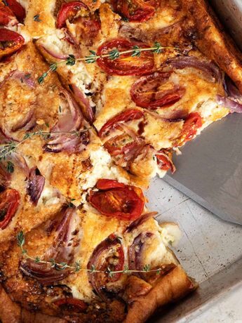 tomato feta Dutch baby in baking pan with spatula