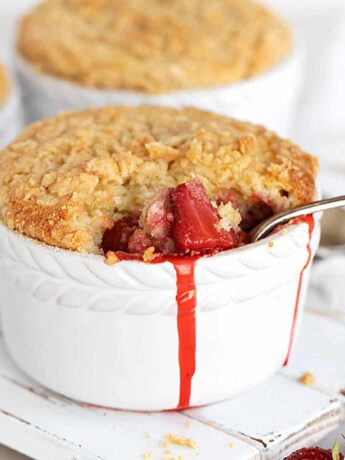 warm strawberry crumb cake in white ramekins with spoon