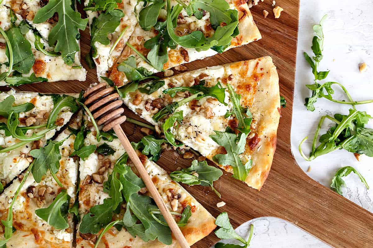 goat cheese white pizza sliced on pizza peel