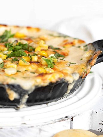 hot corn dip in cast iron pan with baked pita rounds