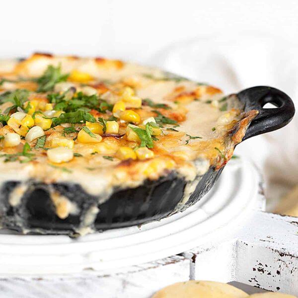 hot corn dip in cast iron pan with baked pita rounds