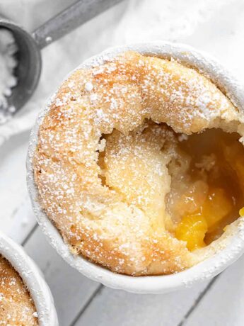 peach pudding cake in white ramekin with spoon