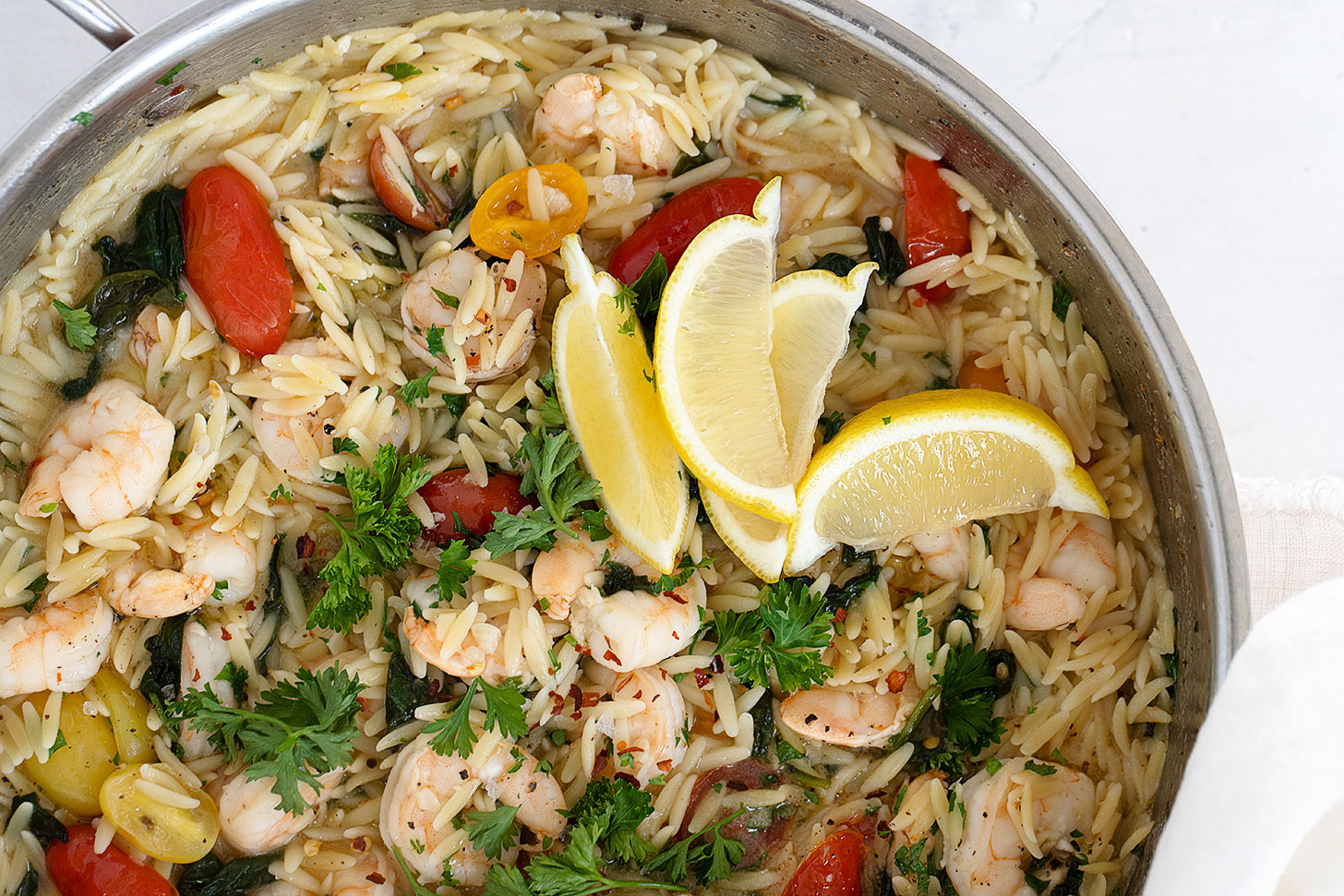 shrimp and orzo with tomatoes and spinach in skillet