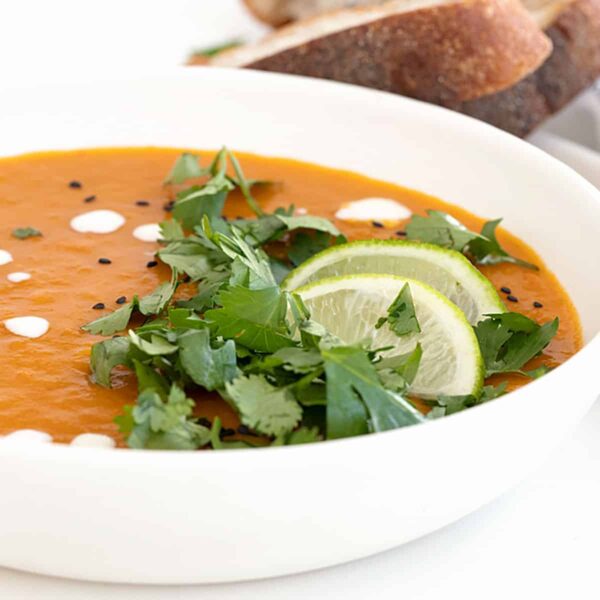 Thai sweet potato soup in bowl with limes and cilantro