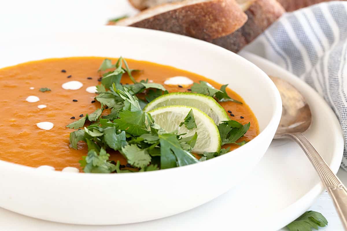 Thai sweet potato soup in bowl with limes and cilantro