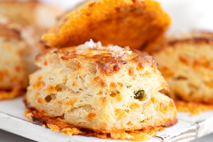 Jalapeño cheddar biscuits stacked on a serving platter.