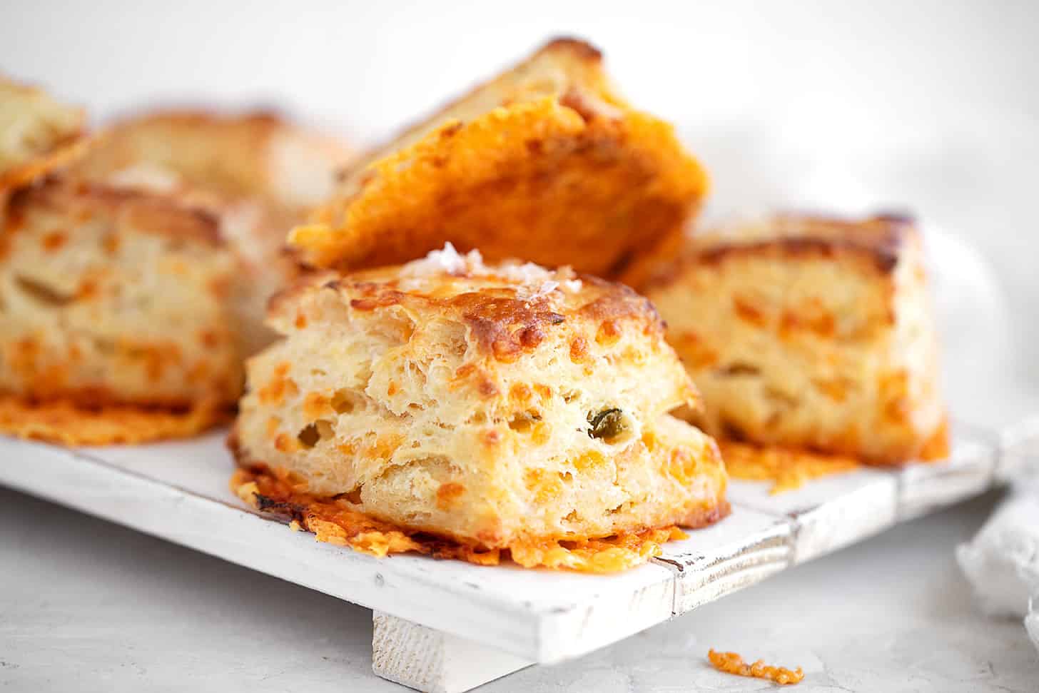Jalapeño cheddar biscuits stacked on a serving platter.