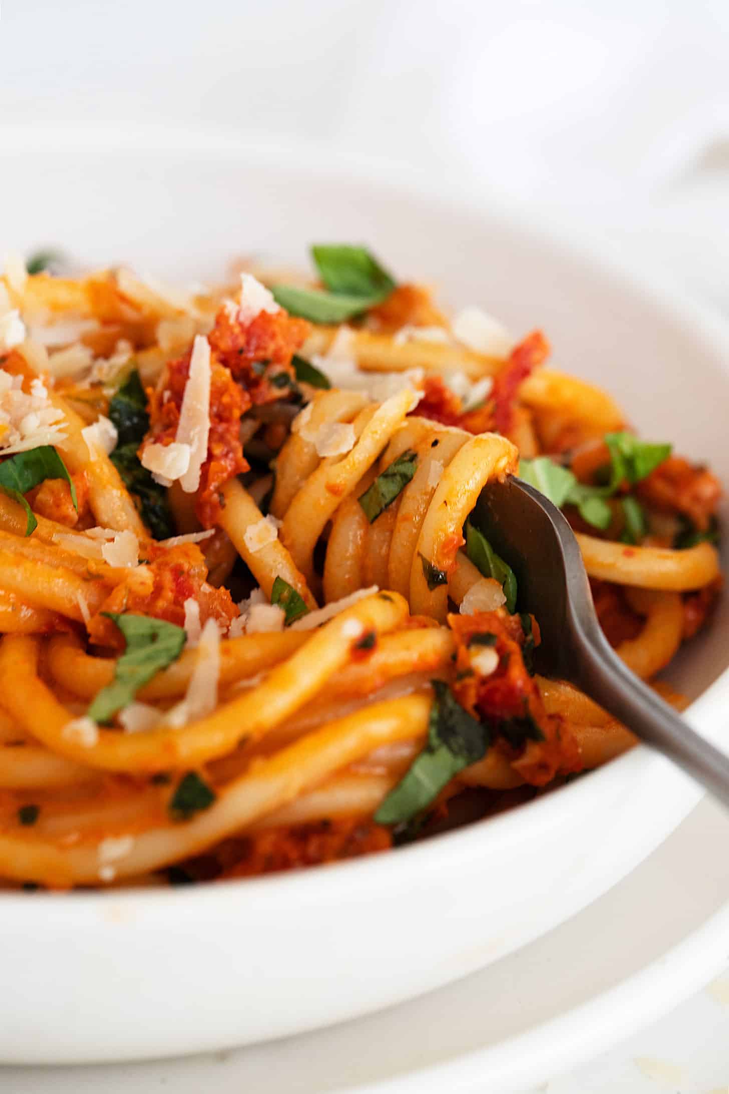 sun dried tomato pasta in white bowl with fork