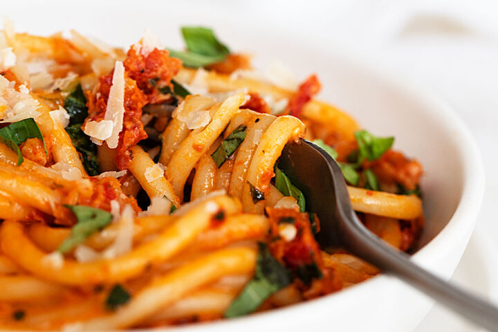 sun dried tomato pasta in white bowl with fork