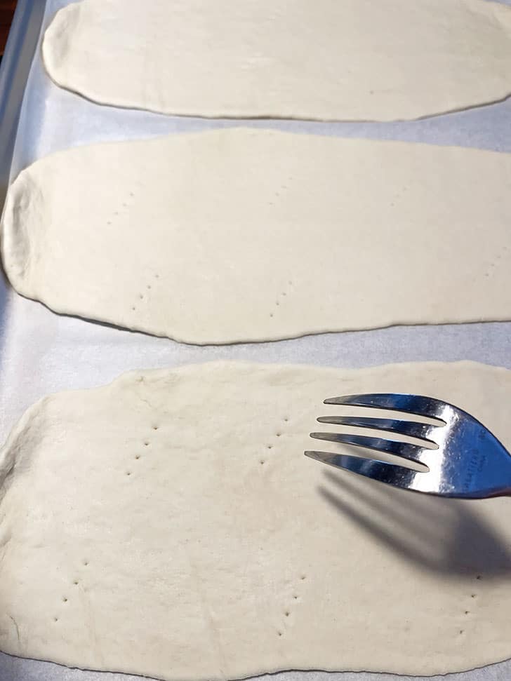 pricking flatbread dough with fork