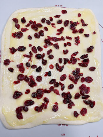 cranberries and lemon curd scattered on rolled dough