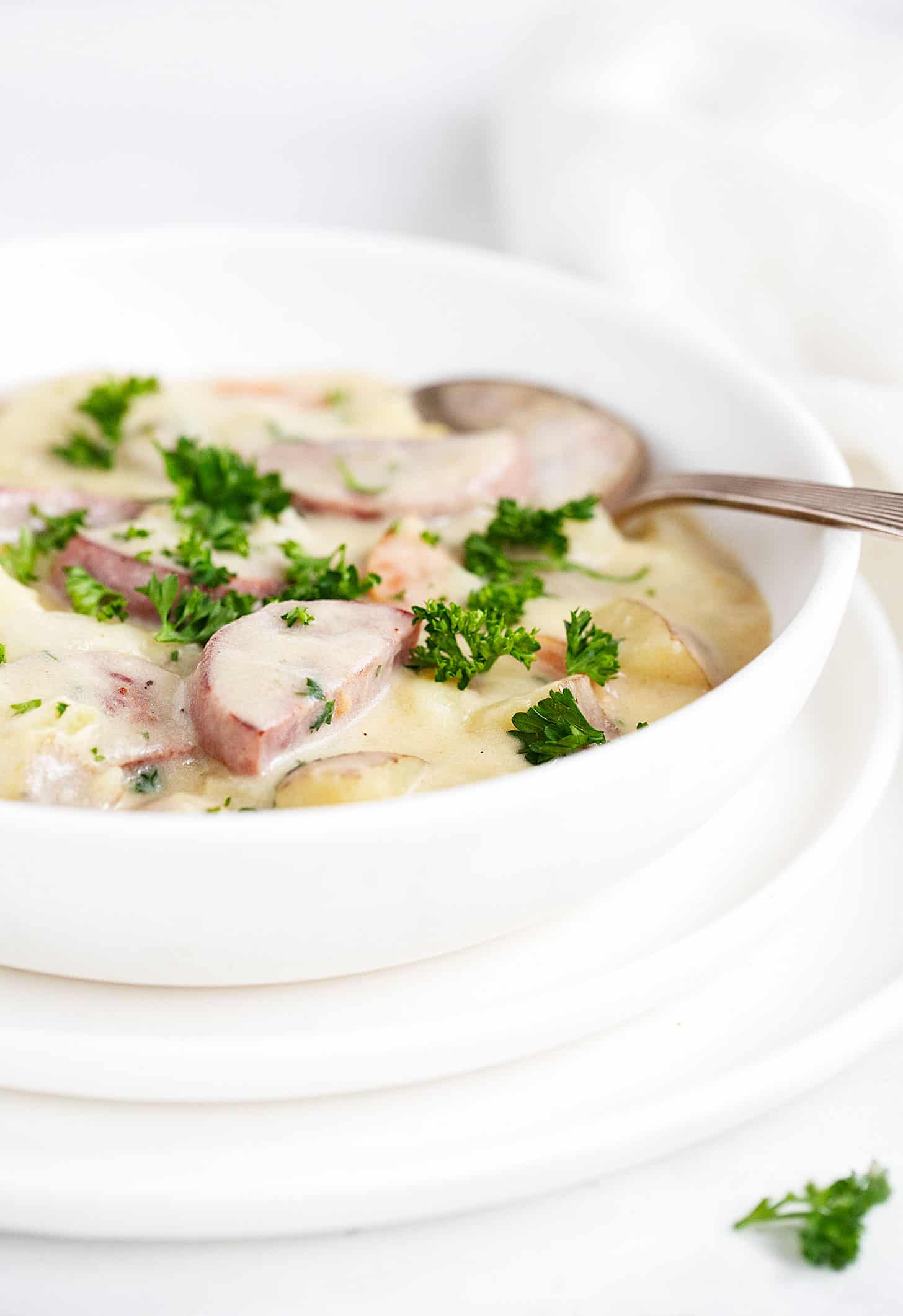 potato kielbasa soup in white bowl with spoon