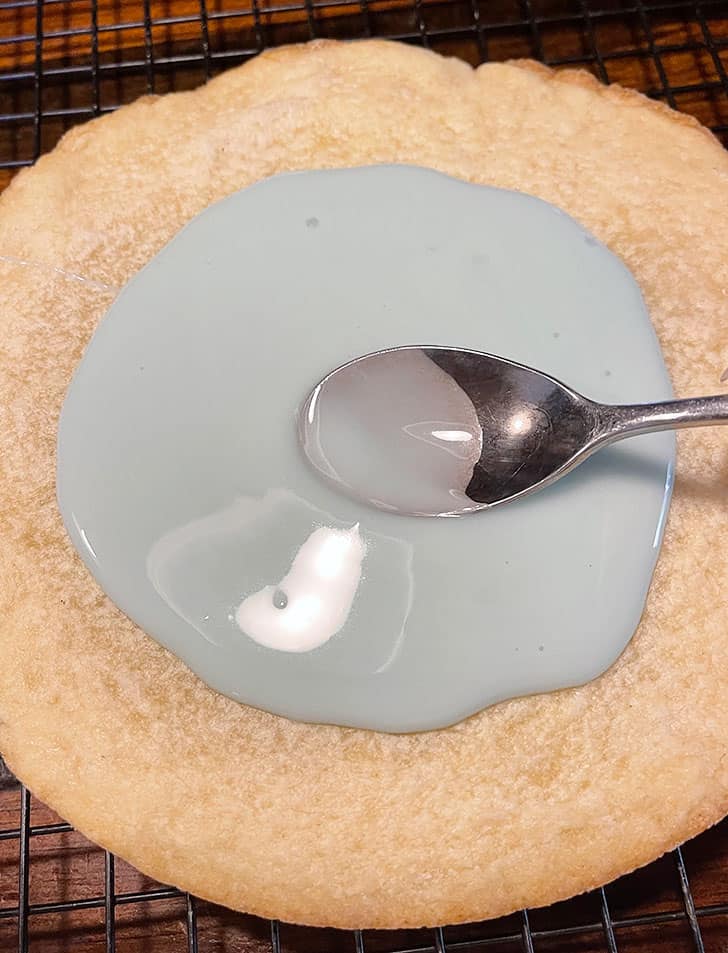 adding glaze to baked and cooled cookie