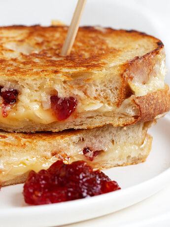 brie grilled cheese with red pepper jelly sliced on white plate