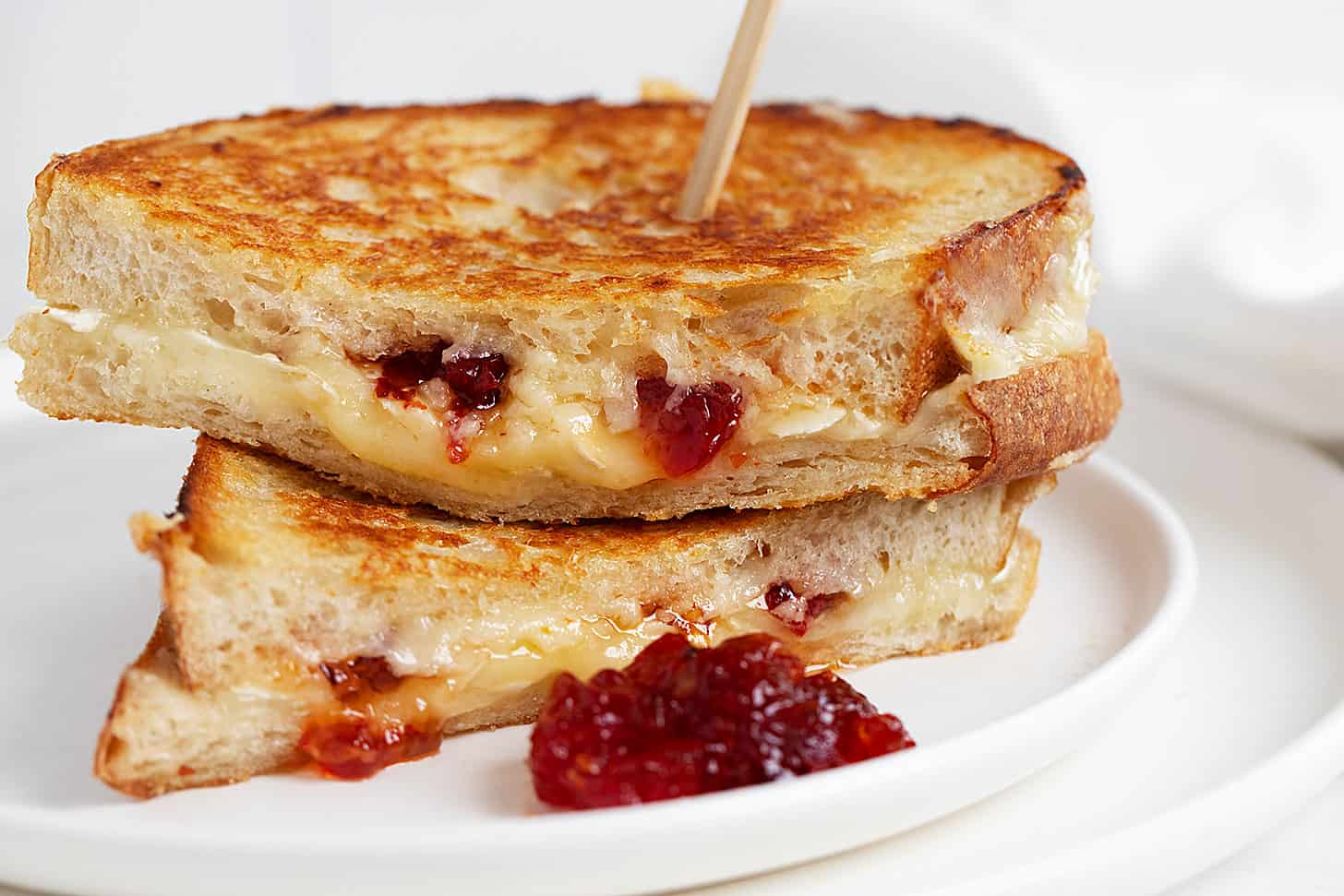 brie grilled cheese with red pepper jelly sliced on white plate