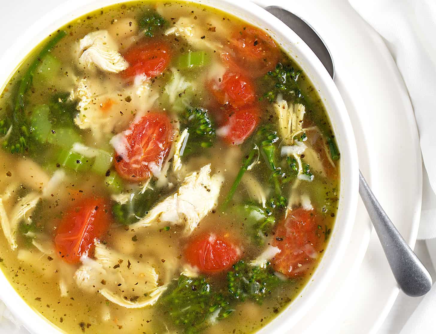 chicken pesto soup in bowl with spoon