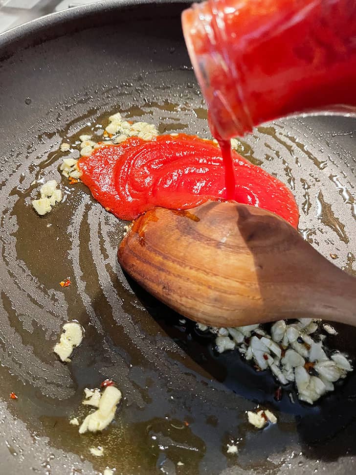 adding passata to sauteed garlic
