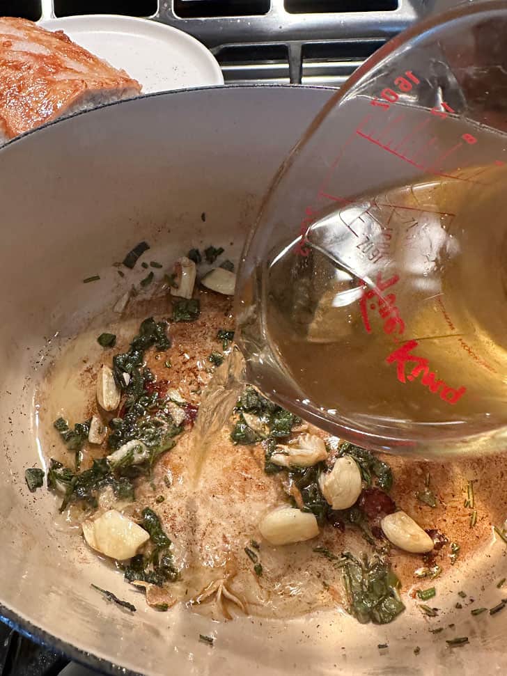 adding wine to sauteed garlic and herbs