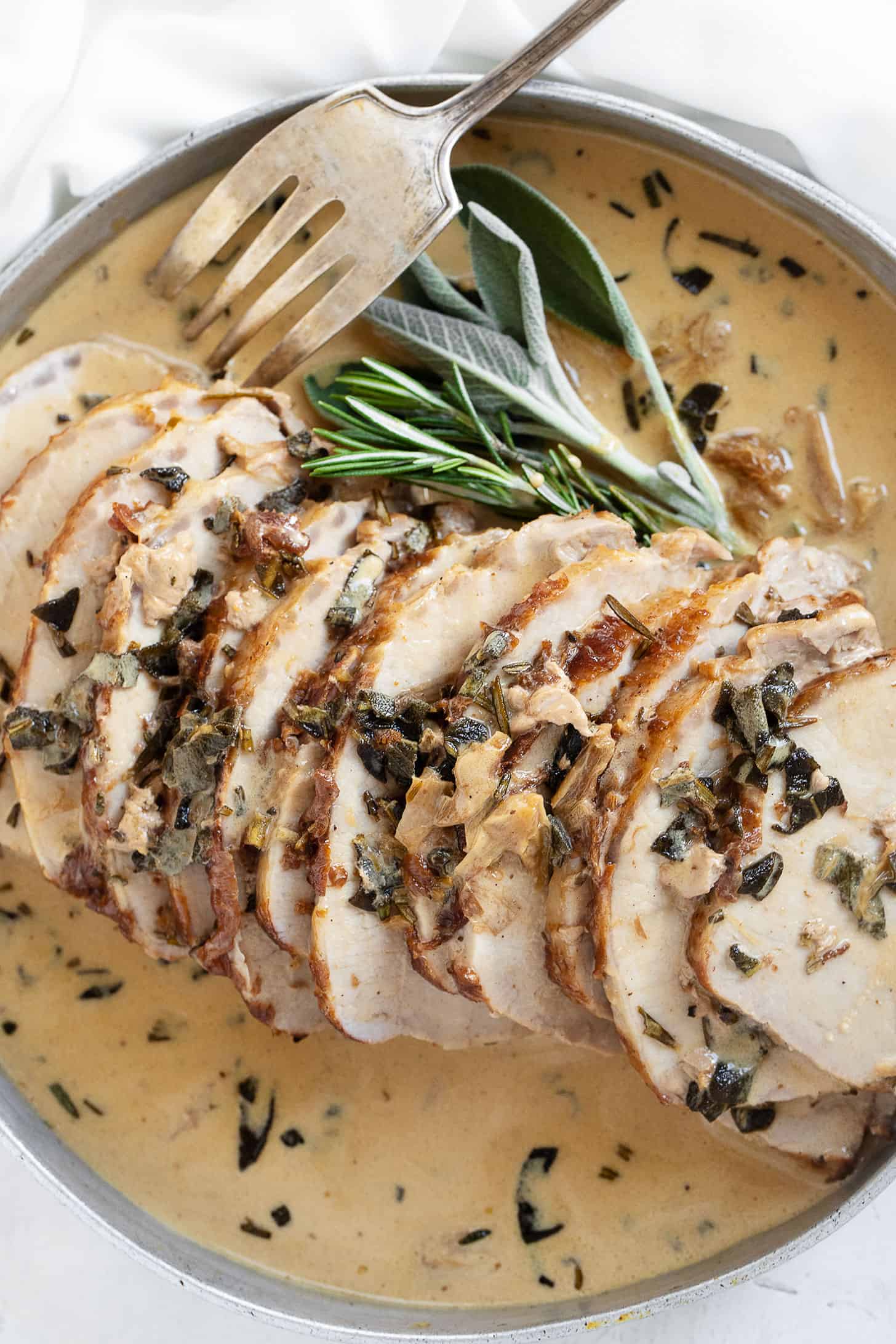 pork loin with wine herb gravy on platter with fork