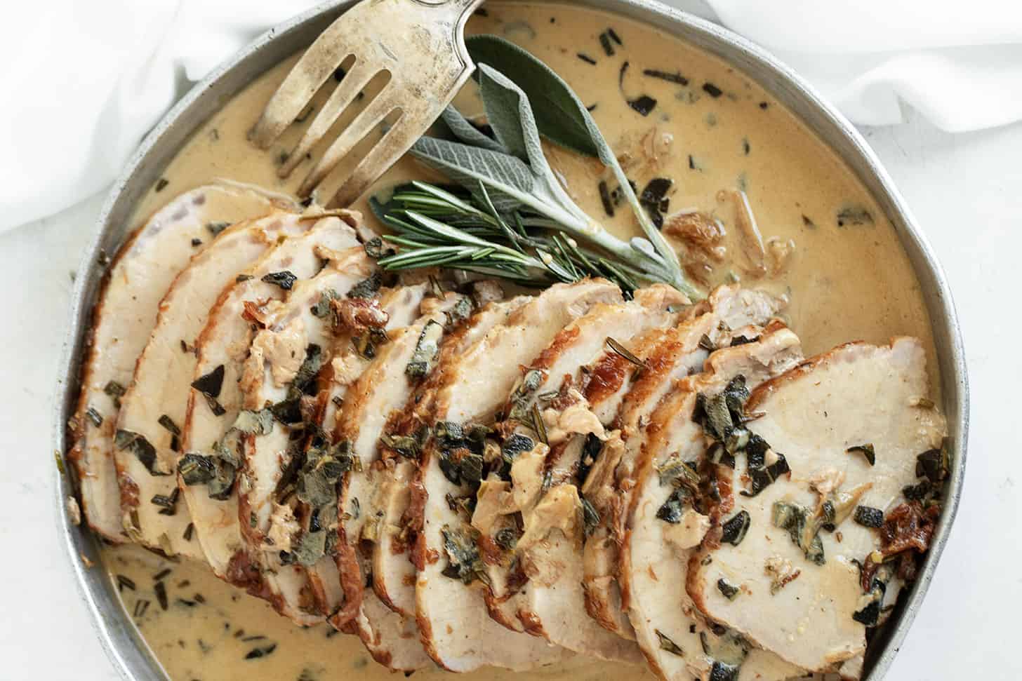 pork loin with wine herb gravy on platter with fork
