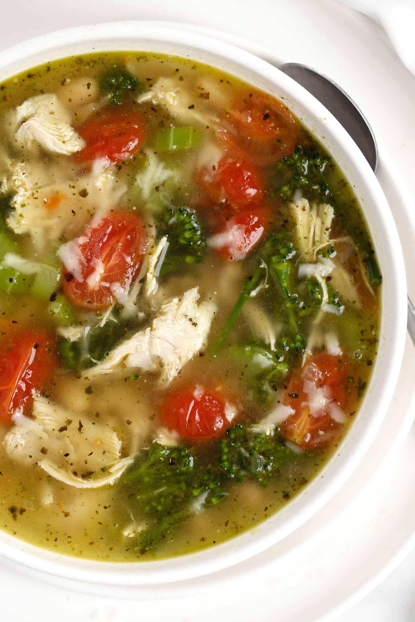 chicken pesto soup in white bowl with spoon