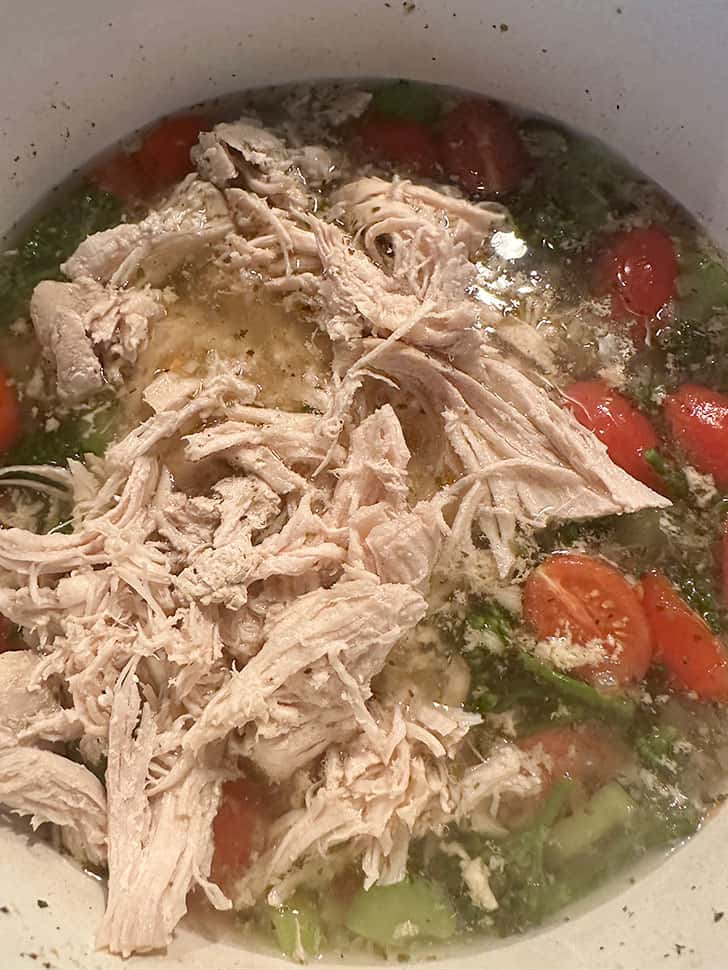 adding shredded cooked chicken to pot