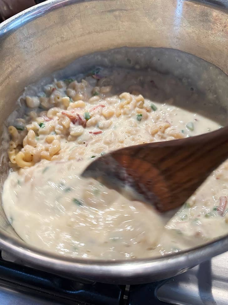 adding sauce to cooked macaroni