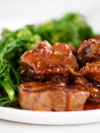 orange pork medallions on plate with broccolini