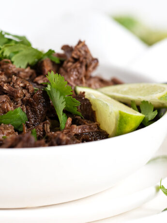 barbacoa in bowl with cilantro and limes