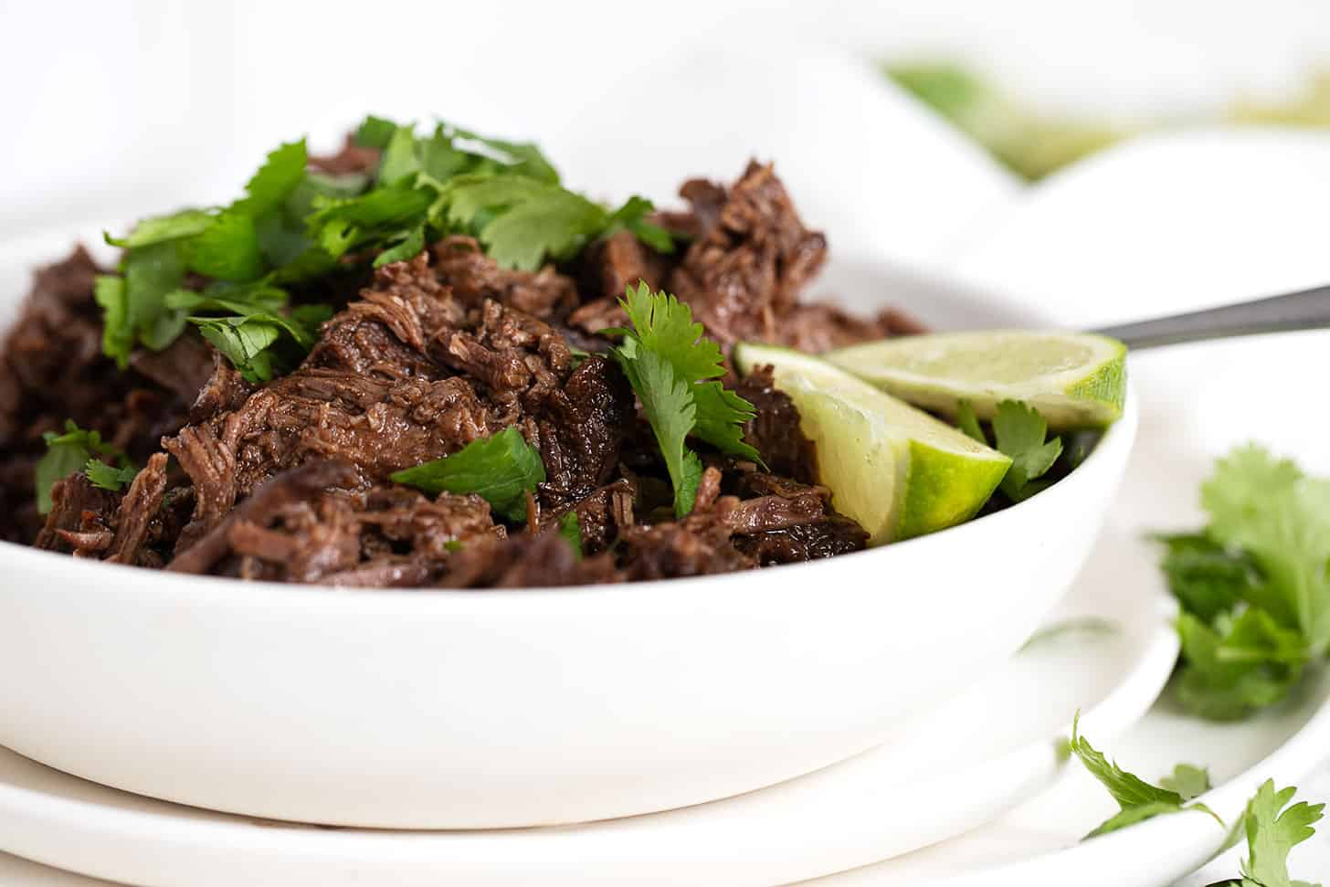 barbacoa in bowl with cilantro and limes