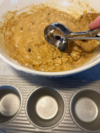 using cookie scoop to scoop batter into muffin tin