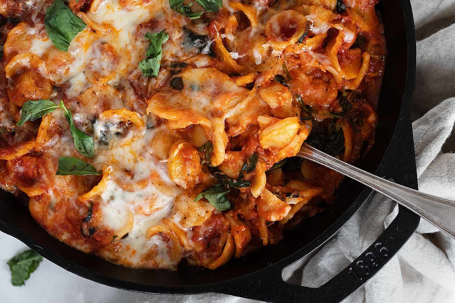 cheesy orecchietta in cast iron skillet with spoon