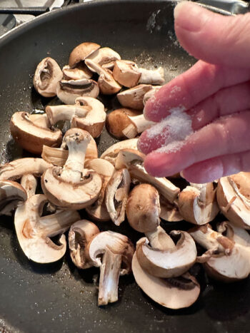 adding salt to mushrooms in skillet