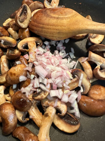 adding shallot to mushrooms in pan