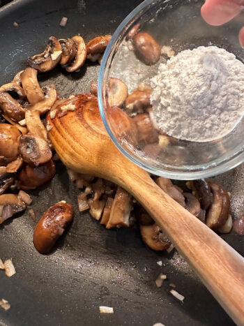 adding flour to mushrooms in pan