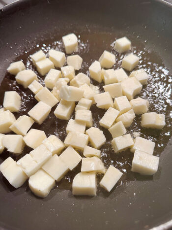 adding halloumi to hot oil in frying pan