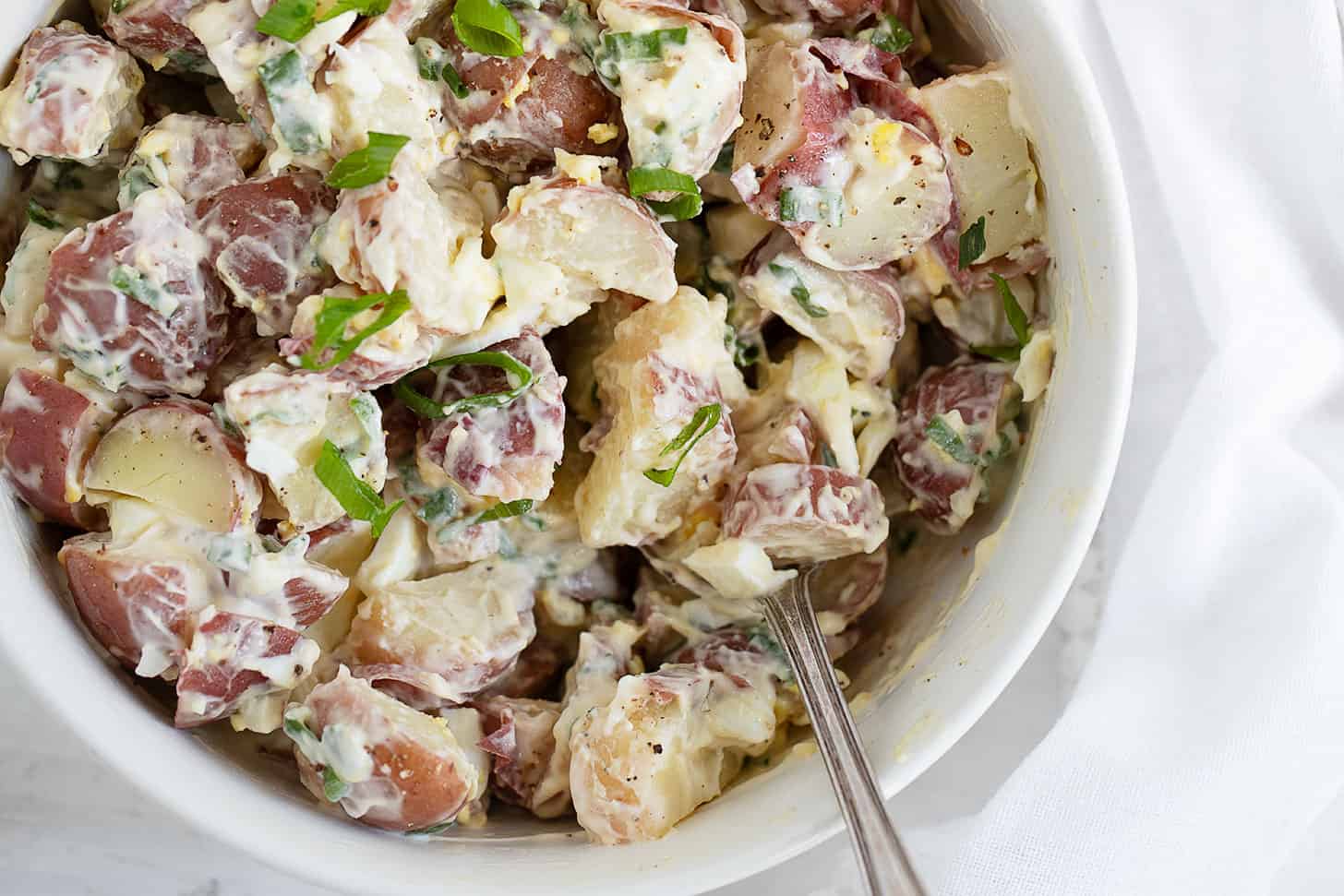 simple potato egg salad in white bowl with spoon