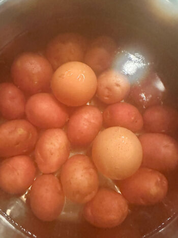 adding eggs to pot with potatoes