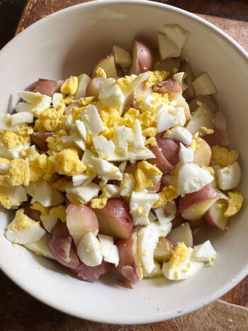 adding chopped egg to potatoes