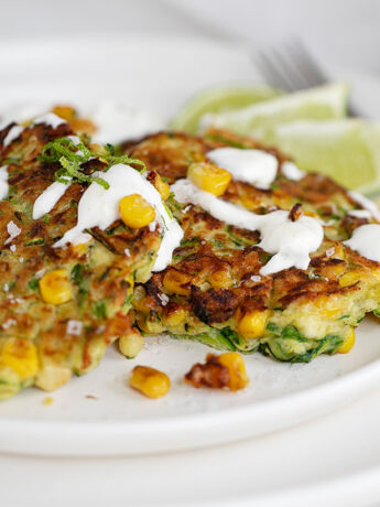 zucchini corn fritters on plate with sour cream drizzle