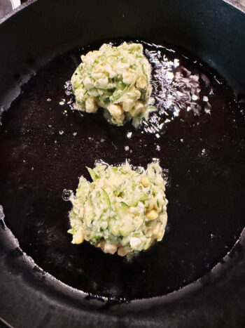two fritters in skillet before spreading out