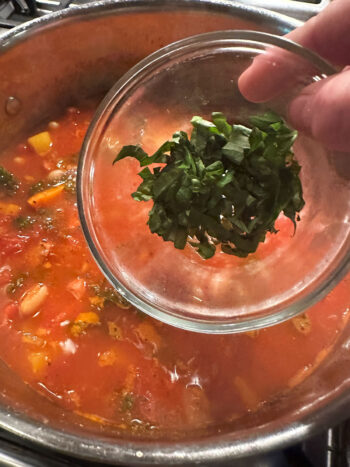 Adding basil to the pot.