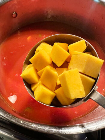 Adding diced butternut squash to the pot.