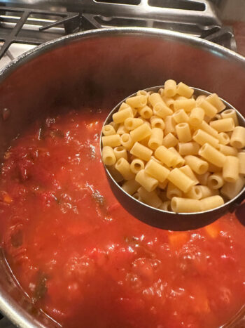 Adding pasta to the pot.