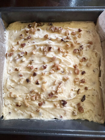 Batter in baking pan with more walnuts on top.